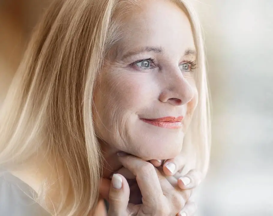 Frau in der Menopause mit grauen Haaren lächelt